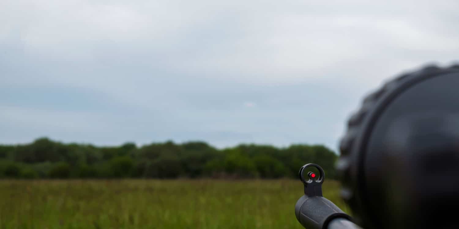 Close up shot down the barrel depicting hunting using an air rifle with scope.