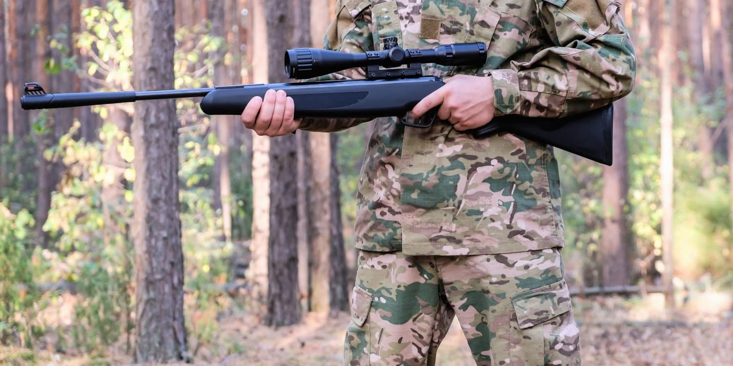 hunter standing in forest with an air rifle